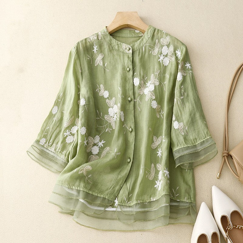 Grüne Damenbluse mit floraler Stickerei, Stehkragen und Knopfleiste auf Holzbügel. Elegante Mode, ideal für Frühling und Sommer.