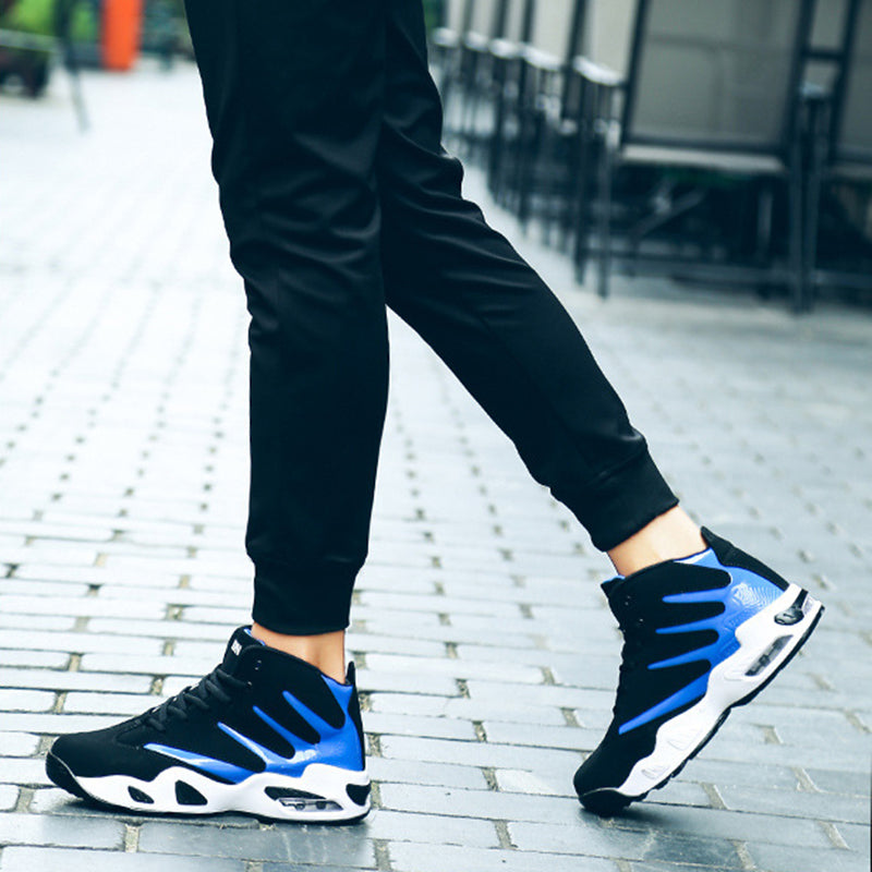Schwarze und blaue Sportschuhe auf gepflastertem Gehweg, getragen von Person in schwarzer Hose. Trendige Sneaker, urbaner Stil, Outdoor-Mode.