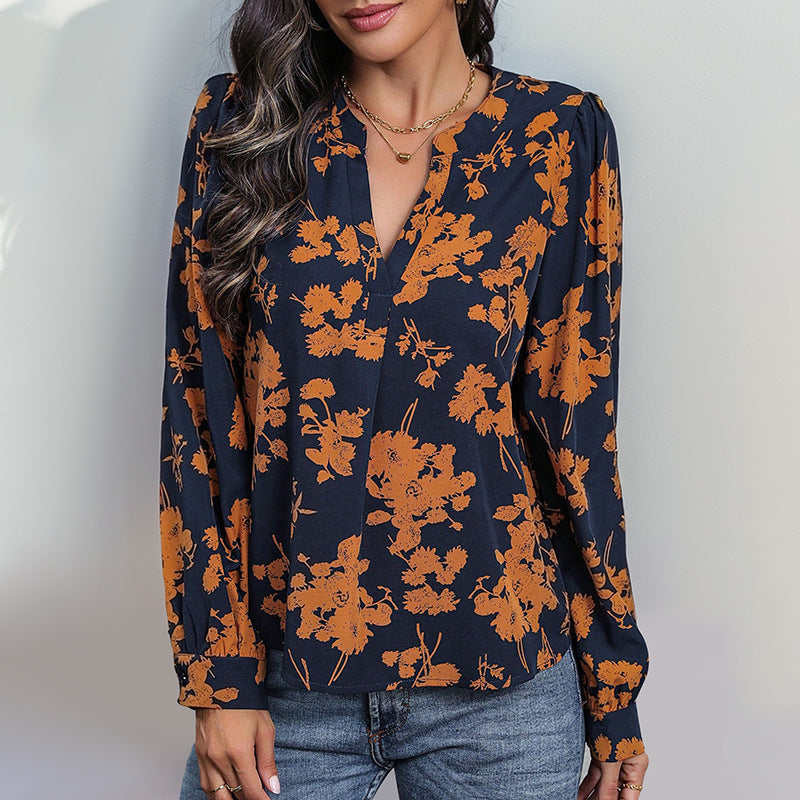 Frau trägt dunkelblaue Bluse mit orangefarbenem Blumenmuster, kombiniert mit Jeans. Modetrend, Damenmode, stilvolle Herbstbekleidung.