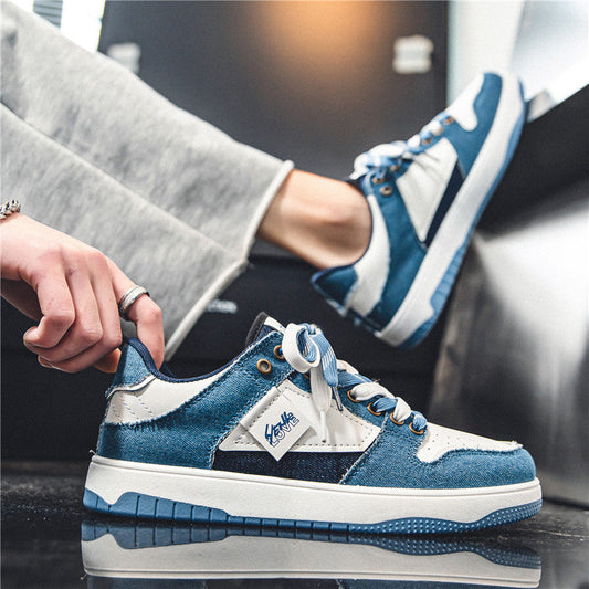 Blaue und weiße Sneaker mit Jeansstoff-Design, getragen von einer Person in grauer Hose. Modische Freizeitschuhe, urbaner Stil, Nahaufnahme.