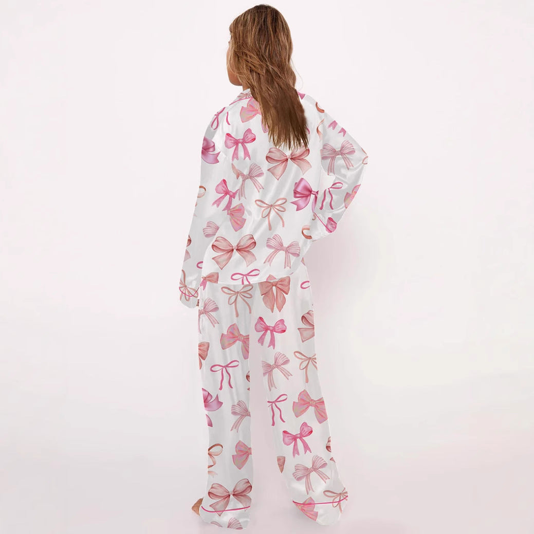 Frau in weißem Pyjama mit rosa Schleifenmuster, Rückansicht. Bequeme Nachtwäsche, modisches Design, ideal für Damen.