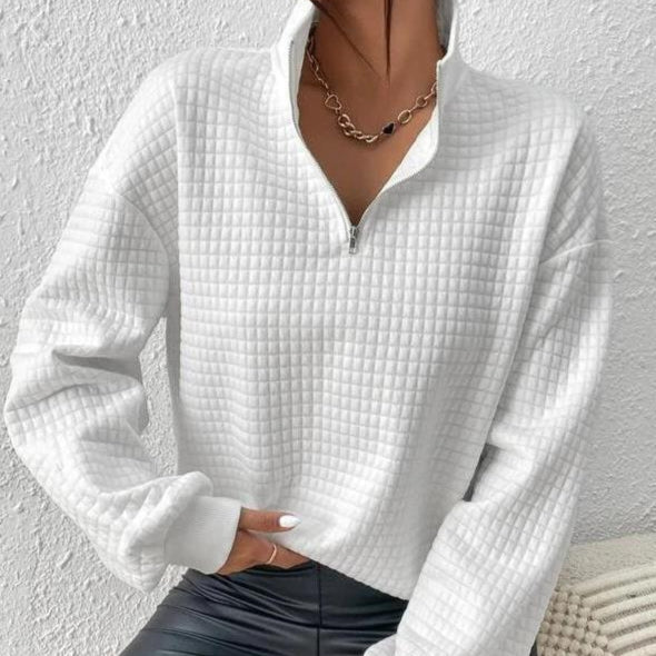 Weiße gesteppte Damen-Sweatshirt mit Reißverschluss, kombiniert mit schwarzer Lederhose und Halskette. Modetrend, bequeme Freizeitkleidung.