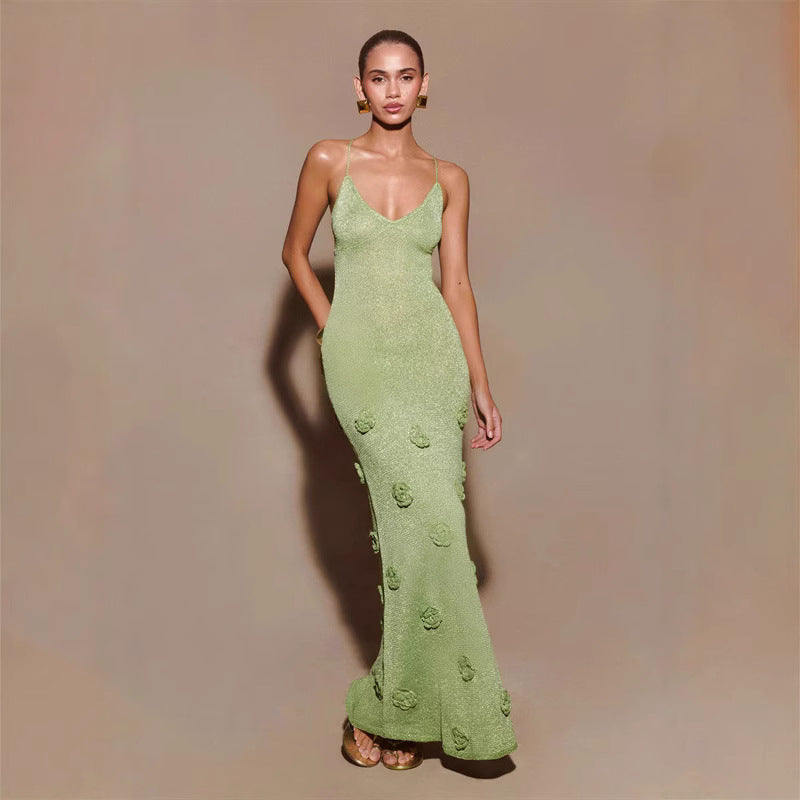 Frau in elegantem, grünem Abendkleid mit Blumenmuster, posiert vor neutralem Hintergrund. Mode, Abendgarderobe, stilvolles Design.