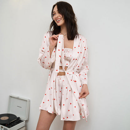 Frau in weißem Pyjama-Set mit roten Herzen, lächelnd, vor einem Plattenspieler. Bequeme Nachtwäsche, modisches Design, entspannte Atmosphäre.