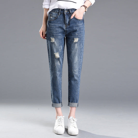 Frau trägt blaue, zerrissene Jeans im Boyfriend-Stil, kombiniert mit weißen Sneakers. Modetrend, lässiger Look, Damenjeans, Streetwear.
