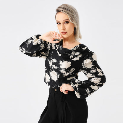 Frau in schwarzer Bluse mit weißem Blumenmuster, posiert vor weißem Hintergrund. Modetrend, Damenbekleidung, stilvolle Bluse.