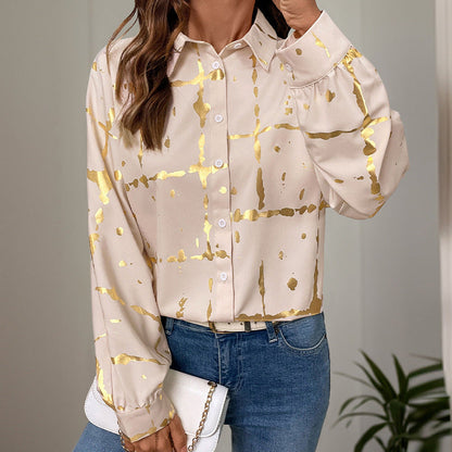 Frau trägt stilvolle, cremefarbene Bluse mit goldenen Akzenten, kombiniert mit blauen Jeans. Elegantes Outfit, modische Damenbekleidung.