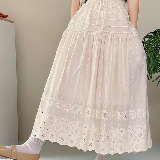 Weiße, lange Spitzenrock mit floralen Stickereien, getragen von einer Person. Elegantes, romantisches Design, ideal für Sommermode und Boho-Stil.
