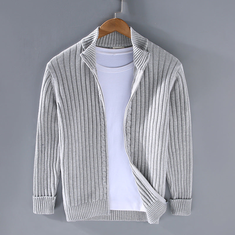 Grauer Strick-Cardigan auf Kleiderbügel vor grauem Hintergrund, kombiniert mit weißem T-Shirt. Modische Herrenbekleidung, lässiger Stil.