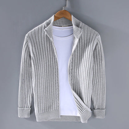 Grauer Strick-Cardigan auf Kleiderbügel vor grauem Hintergrund, kombiniert mit weißem T-Shirt. Modische Herrenbekleidung, lässiger Stil.