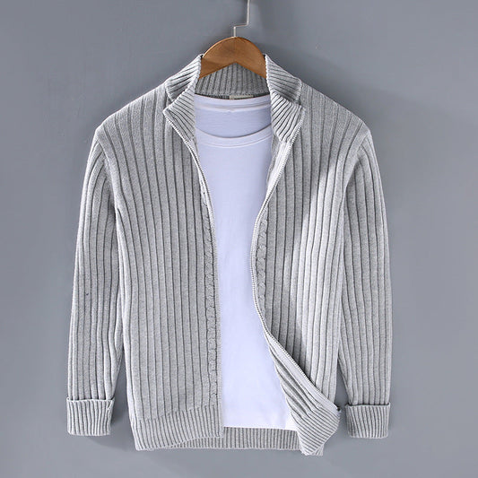 Grauer Strick-Cardigan auf Kleiderbügel vor grauem Hintergrund, kombiniert mit weißem T-Shirt. Modische Herrenbekleidung, lässiger Stil.