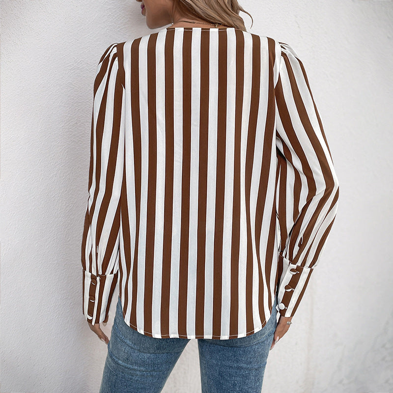 Frau in gestreifter Bluse, braun-weiß, Rückansicht, lässiger Stil, modische Damenbekleidung, vertikale Streifen, Jeans, Wandhintergrund.