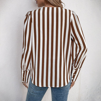 Frau in gestreifter Bluse, braun-weiß, Rückansicht, lässiger Stil, modische Damenbekleidung, vertikale Streifen, Jeans, Wandhintergrund.