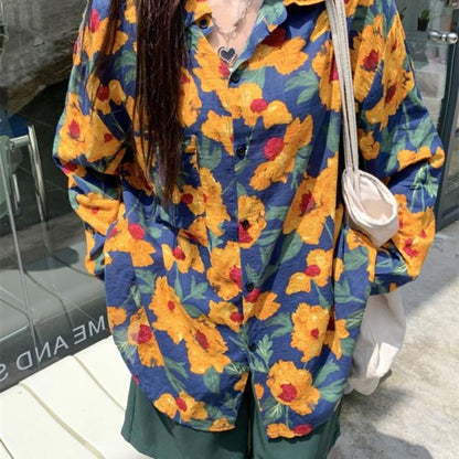Frau in bunter Blumenbluse mit gelben und roten Blumen, trägt weiße Stofftasche. Modetrend, lässiger Stil, Sommermode, Outdoor.