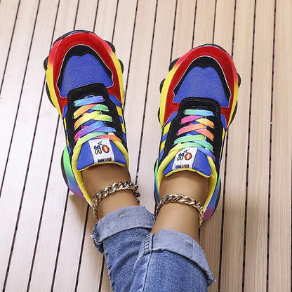 Bunte Sneaker mit Regenbogenfarben, getragen von Person in Jeans, auf Holzboden. Modische Turnschuhe, trendige Schuhe, farbenfrohes Design.