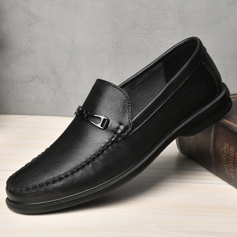 Schwarzer Herren-Loafer aus Leder mit Metallschnalle, elegant und modern, auf Holztisch vor grauer Wand platziert. Ideal für Business und Freizeit.