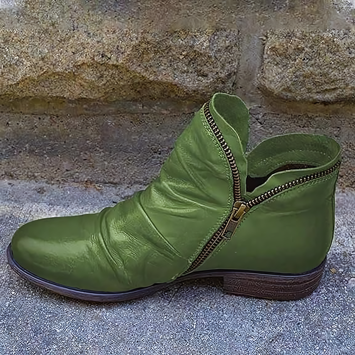 Grüner Lederstiefel mit Reißverschluss, seitlich vor einer Steinmauer. Modischer Damenstiefel, ideal für Herbstmode und Outdoor-Aktivitäten.