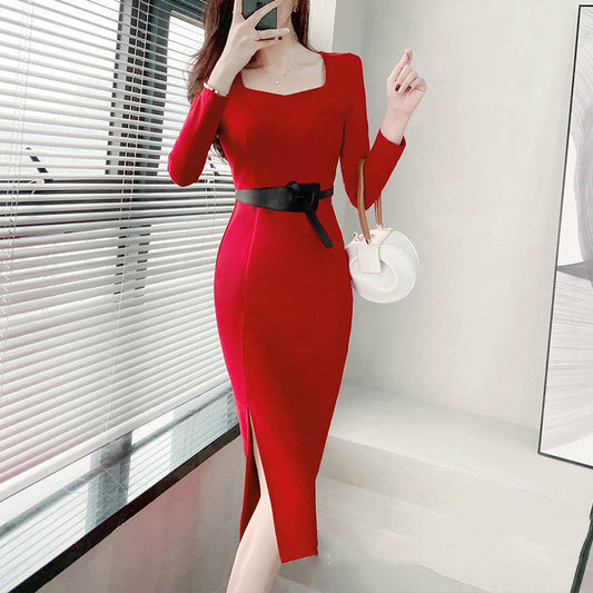 Frau in elegantem roten Kleid mit Gürtel, posiert vor Fenster. Modernes Design, lange Ärmel, Seitenschlitz. Perfekt für Abendmode und Events.