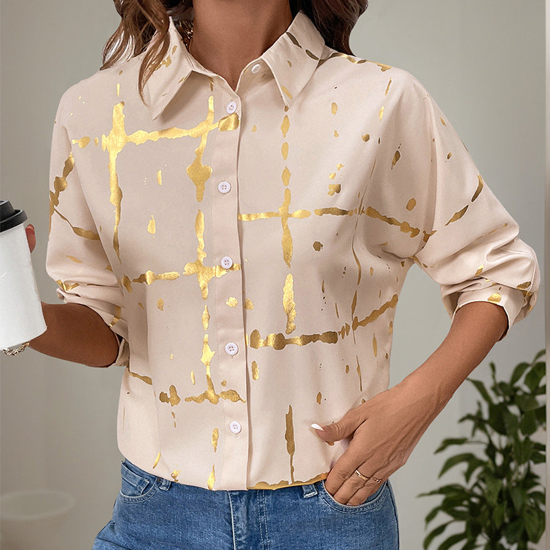 Frau in beiger Bluse mit goldenen Streifen, hält Kaffeebecher. Modetrend, elegante Damenmode, Freizeitlook.
