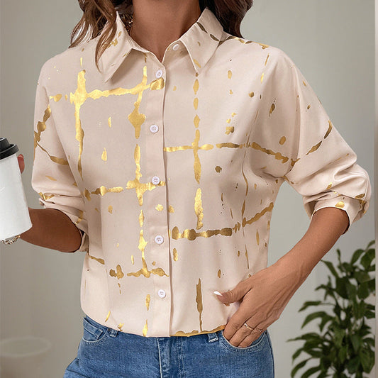 Frau in beiger Bluse mit goldenen Streifen, hält Kaffeebecher. Modetrend, elegante Damenmode, Freizeitlook.