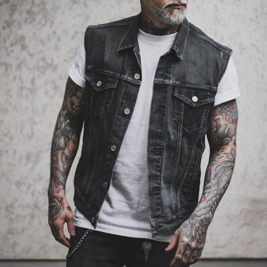 Mann mit tätowierten Armen trägt schwarze Jeansweste und weißes T-Shirt. Moderner Streetwear-Look, lässiger Stil, Mode für Männer.