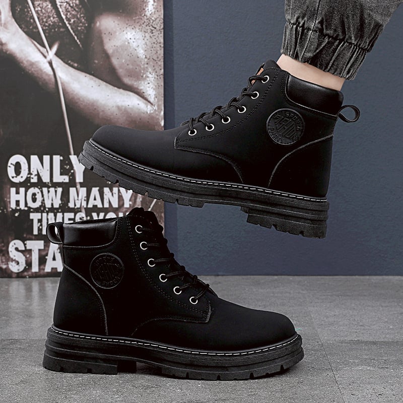 Schwarze Herrenstiefel aus Leder mit Schnürung, robustem Profil und Logo-Detail, getragen auf grauem Boden. Ideal für Outdoor und Wintermode.