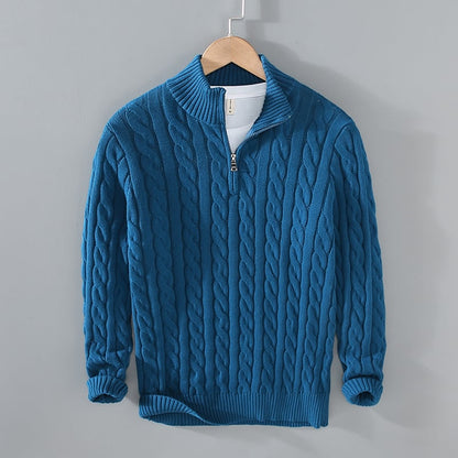 Blauer Strickpullover mit Zopfmuster, Reißverschluss und Stehkragen auf Holzkleiderbügel. Modischer Herrenpullover, warm und stilvoll.