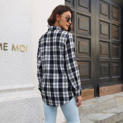 Frau in kariertem Hemd und Jeans vor Holztür, seitlich stehend. Modetrend, lässiger Stil, Herbstmode, urbane Kleidung, Streetwear.