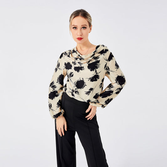 Frau in eleganter Bluse mit schwarzem Blumenmuster und schwarzer Hose vor weißem Hintergrund. Modetrend, Damenbekleidung, stilvolles Outfit.