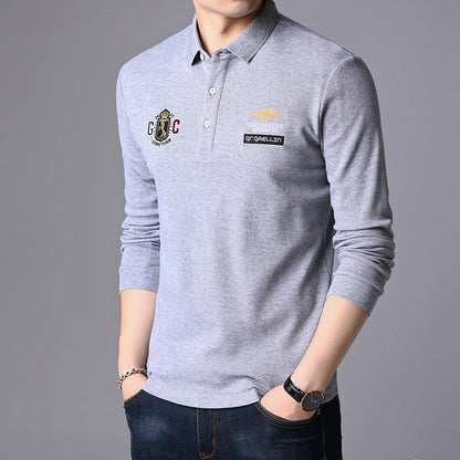 Graues Herren-Poloshirt mit langen Ärmeln, besticktem Logo und Emblem, kombiniert mit blauer Jeans. Elegante Freizeitmode für Männer.