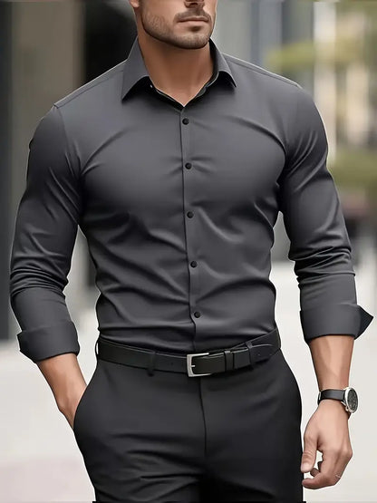 Eleganter Mann in grauem Hemd und schwarzer Hose, trägt eine Uhr und Gürtel. Businessmode, stilvoller Look, urbane Umgebung.