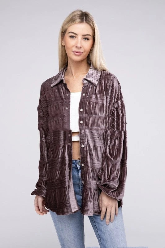 Frau in brauner, strukturierter Bluse und blauer Jeans vor grauem Hintergrund. Modetrend, Damenbekleidung, lässiger Stil.