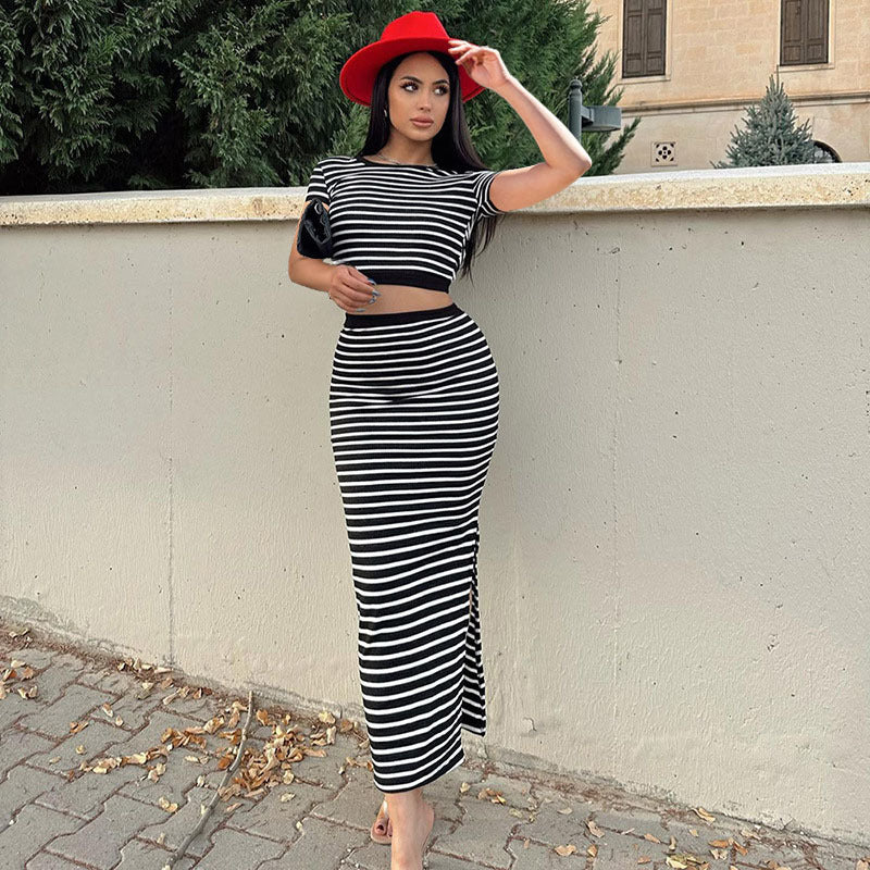 Frau in gestreiftem Kleid und rotem Hut lehnt an einer Mauer. Modetrend, eleganter Look, Herbstmode, stilvolle Kleidung, Streetstyle.