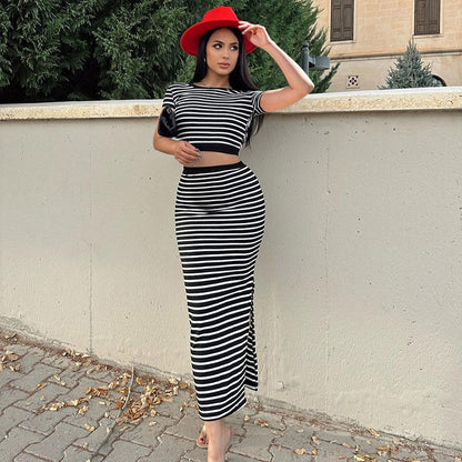 Frau in gestreiftem Kleid und rotem Hut lehnt an einer Mauer. Modetrend, eleganter Look, Herbstmode, stilvolle Kleidung, Streetstyle.