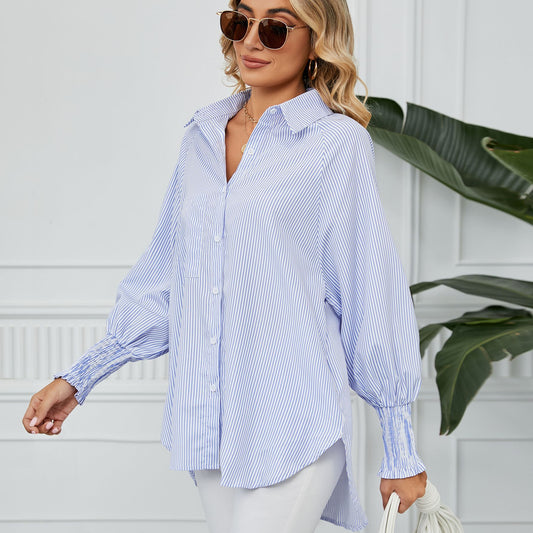 Frau in gestreifter Bluse und Sonnenbrille, lächelnd, vor weißer Wand mit Pflanzen. Modetrend, Damenmode, lässiger Stil, Sommeroutfit.
