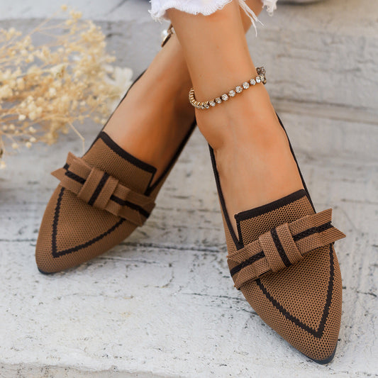 Braune Damen-Loafer mit Schleifen-Detail, spitze Form, auf hellem Steinboden. Modische Schuhe, elegantes Design, ideal für den Herbst.