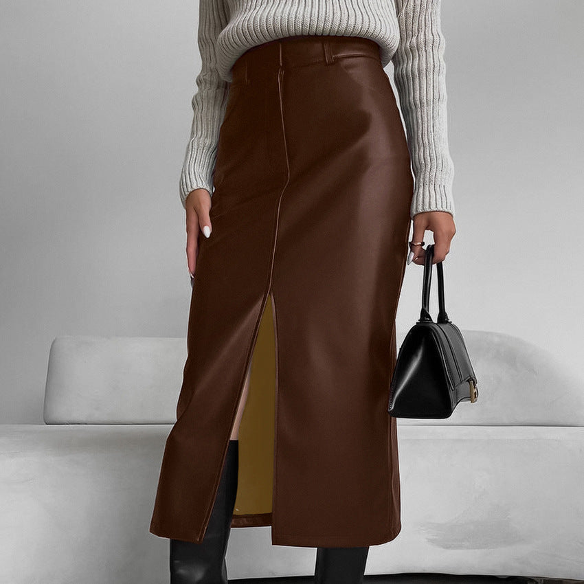 Dame in braunem Lederrock mit Schlitz, grauem Strickpullover und schwarzer Handtasche. Modetrend Herbst, eleganter Look, stilvolle Damenmode.