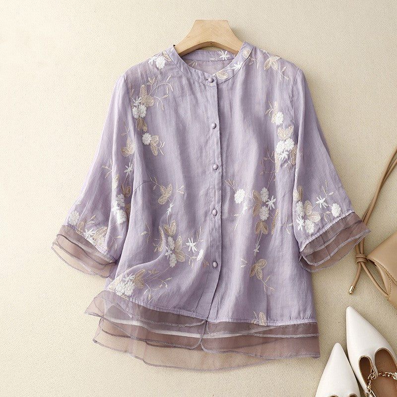 Lila Damenbluse mit floraler Stickerei, transparenten Ärmeln und Knopfleiste, elegant und modisch, ideal für Frühling und Sommer.