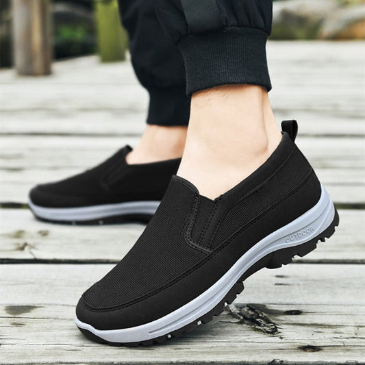 Schwarze Herren-Slip-On-Sneaker auf Holzsteg, bequemes Design, rutschfeste Sohle, ideal für Outdoor-Aktivitäten und Freizeitkleidung.