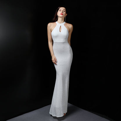 Frau in elegantem, weißem Abendkleid mit Neckholder und Schlüssellochausschnitt, posiert vor schwarzem Hintergrund. Mode, Abendgarderobe, Eleganz.