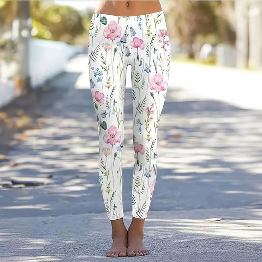 Frau trägt weiße Leggings mit rosa Blumenmuster, steht barfuß auf einer sonnigen Straße. Modische Damenbekleidung, florales Design, Freizeitlook.