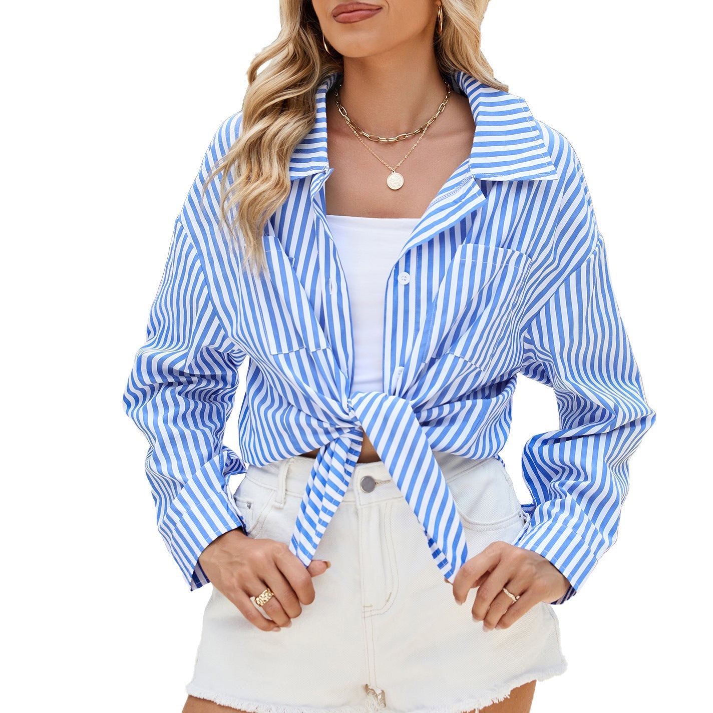 Frau trägt blau-weiß gestreiftes Hemd, geknotet vorne, über weißem Top und weißen Shorts. Sommermode, lässiger Stil, trendige Damenbekleidung.