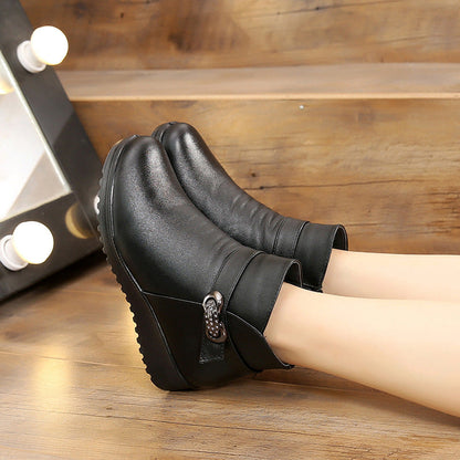 Schwarze Damen-Stiefeletten mit Keilabsatz, seitlicher Schnalle und rutschfester Sohle auf Holzboden. Elegante, bequeme Herbst-Winterschuhe.