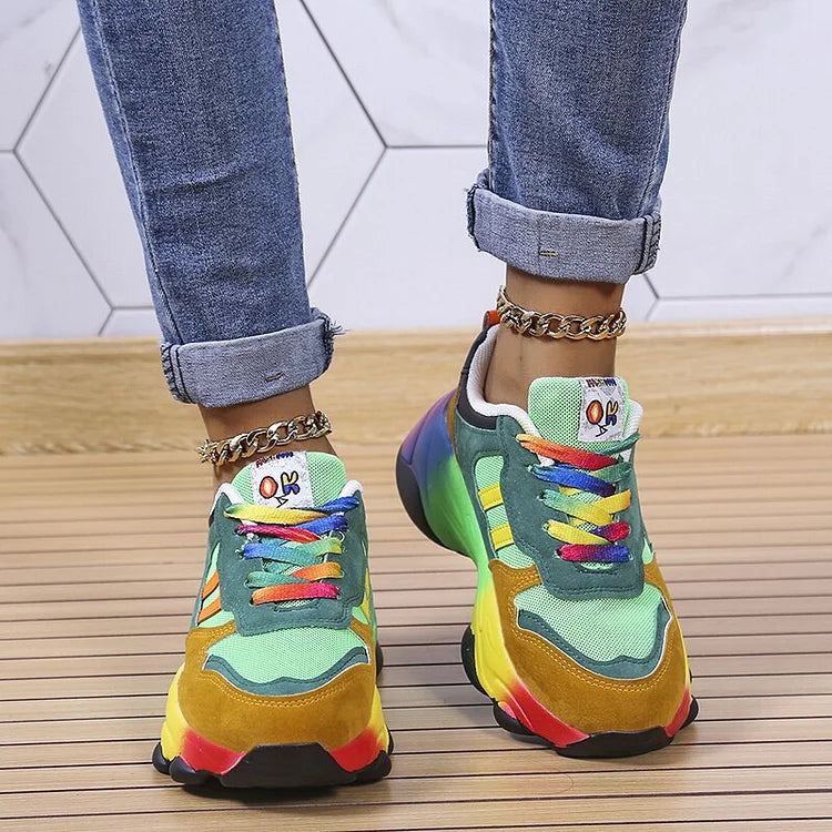 Bunte Sneaker mit Regenbogenfarben, getragen von Person in Jeans. Modische Turnschuhe, auffälliges Design, ideal für trendige Streetwear-Looks.