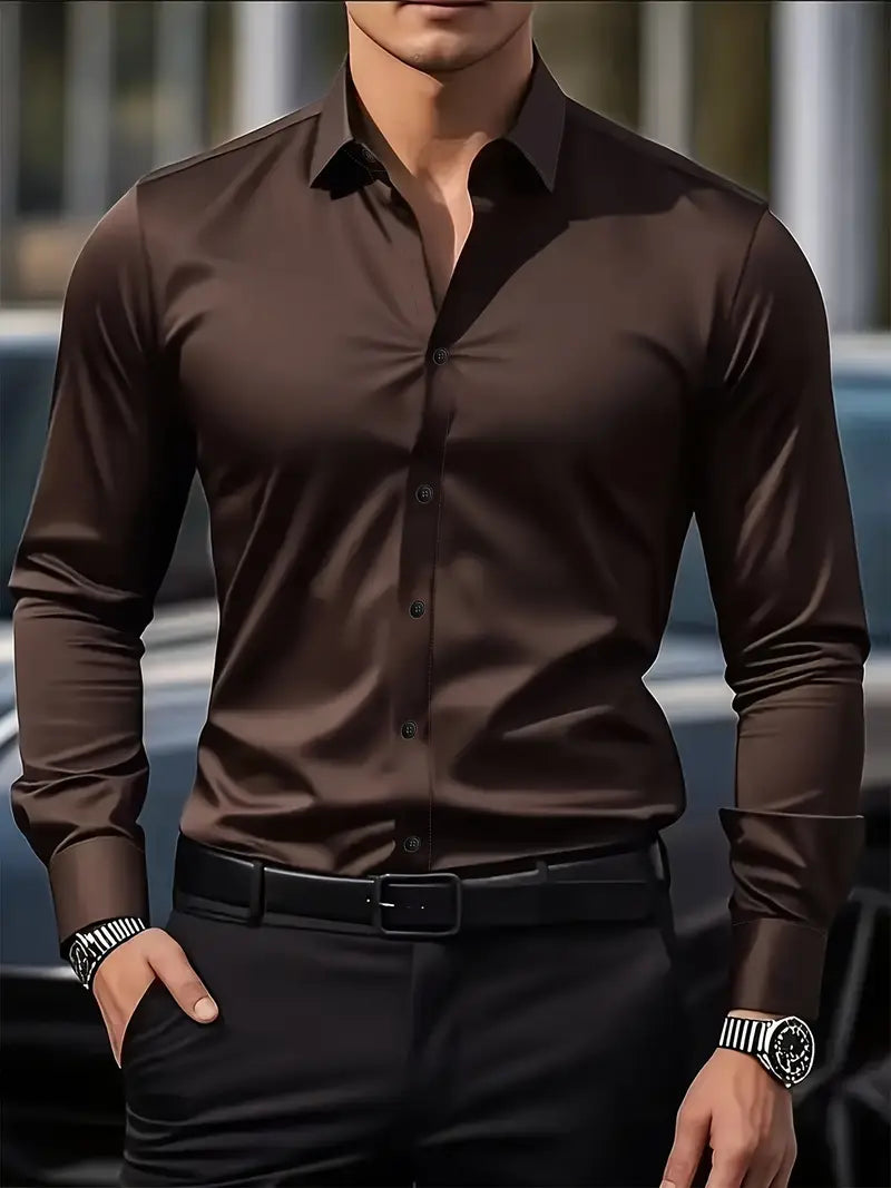 Mann in eleganter, dunkelbrauner Hemd, schwarze Hose, Armbanduhr, vor unscharfem Hintergrund. Mode, Herrenbekleidung, stilvoll, modern.