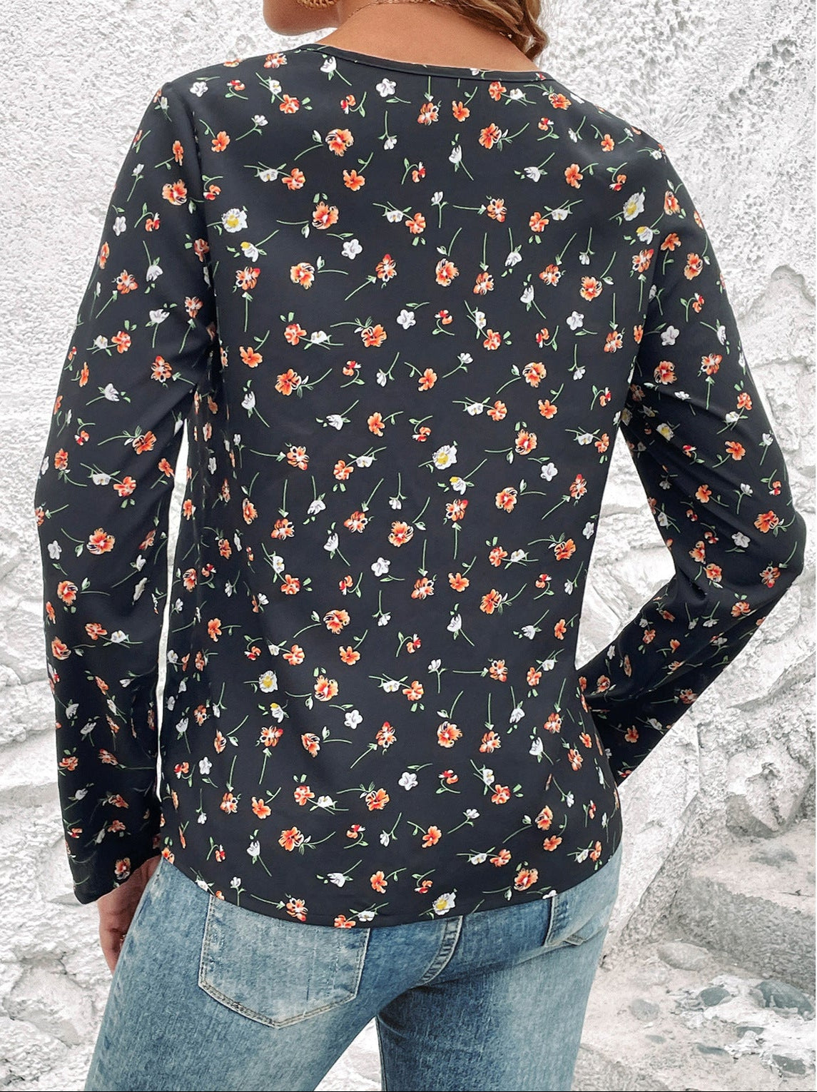 Damen-Langarmshirt mit floralem Muster, schwarze Basis, rote und weiße Blumen, lässiger Stil, kombiniert mit blauen Jeans, Rückansicht.