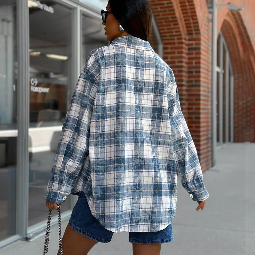 Frau in kariertem Hemd und Jeansshorts, geht an Backsteingebäude vorbei. Streetstyle, Mode, lässiger Look, urbane Umgebung.