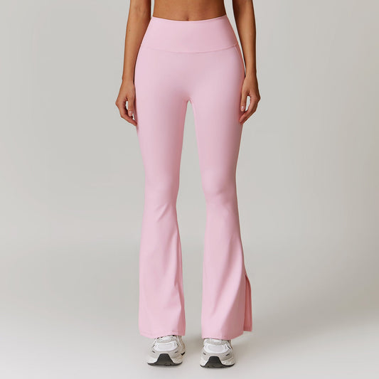 Frau in rosa Schlaghose und weißen Turnschuhen vor grauem Hintergrund. Modetrend, Damenbekleidung, Fitnessmode, bequeme Sporthose.
