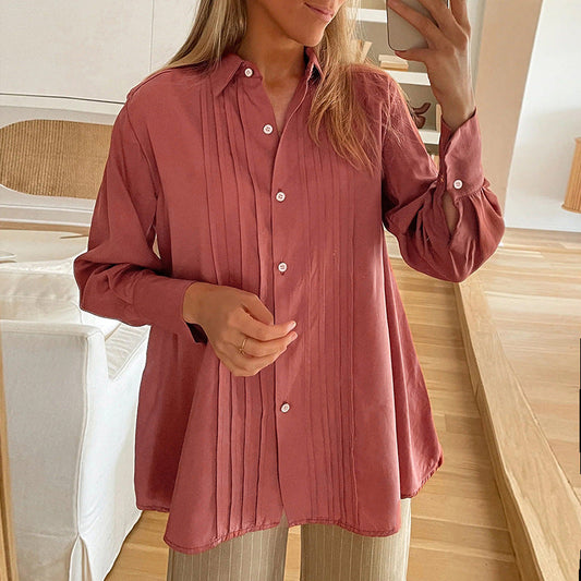 Frau in rosa Bluse mit Falten, steht in modernem Wohnzimmer, hält Smartphone. Stilvolle Damenmode, Freizeitlook, Innenraum, Selfie.