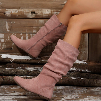 Damenbeine in rosa Wildlederstiefeln, lässig auf Holzbank. Modische Herbststiefel, bequem und stilvoll. Perfekt für trendige Outfits.